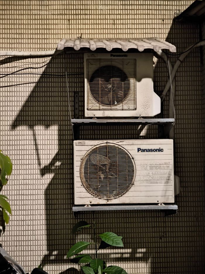 Close-up of two air conditioning units on a building facade in sunlight.